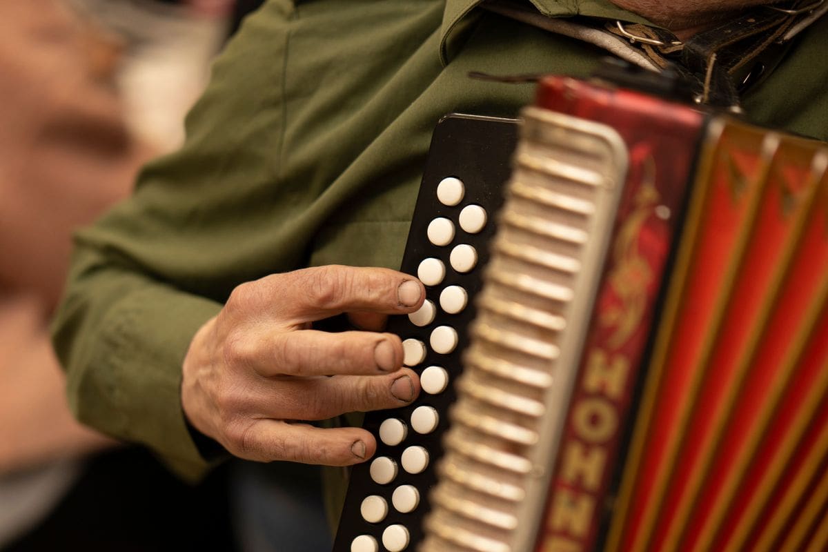 A musician playing a red button-box accordion